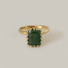 a gold ring with a green stone in the middle