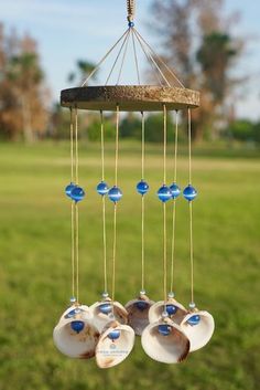 three seashells hanging from a wind chime with blue glass beads on them