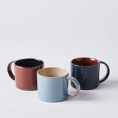 three different colored coffee mugs sitting next to each other