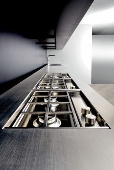 a stainless steel kitchen sink and counter top in a room with white walls, black flooring and an angled ceiling