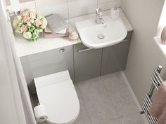 a white toilet sitting next to a sink in a bathroom under a vanity with a mirror above it