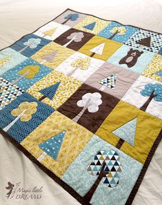 a close up of a quilt on a bed with white sheets and blue and yellow colors