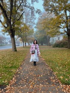 a woman walking down a leaf covered path