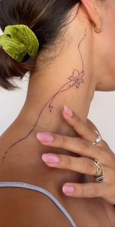 a woman with a flower tattoo on her neck and behind her head is a green leaf