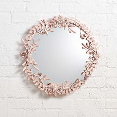 a mirror that is on the wall with some flowers in front of it and a brick wall behind it