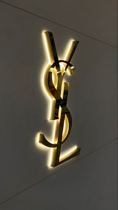 the ysl logo is lit up against a white wall with yellow lights on it