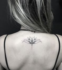 the back of a woman's neck with a flower tattoo on it