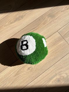 a green and white ball with the number six on it sitting on a wooden floor