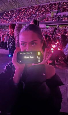 a woman taking a photo with her cell phone in front of an audience at a sporting event