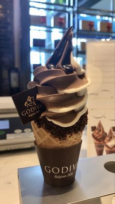 an ice cream sundae is topped with chocolate and white icing on a counter