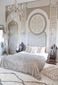 a large bed sitting under a chandelier next to a white rug on top of a floor