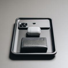 an apple product is sitting on a tray with other items in the tray, as well as a leather wallet