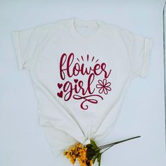 a white t - shirt that says flower girl on it with flowers in front of it