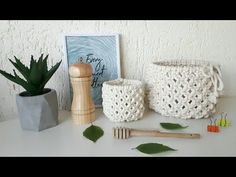 three crocheted baskets and two bamboo toothbrushes on a white table next to a green plant