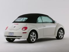 a white and black convertible car parked in front of a white wall with the top down