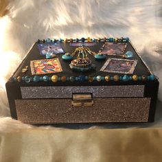 a black box with pictures and beads on it sitting on a white furnishing