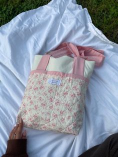 a person laying on the ground with a pink and white tote bag next to it