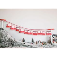 a red and white train traveling down tracks next to snow covered ground with buildings on each side