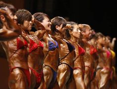 a group of women standing next to each other in bikinis