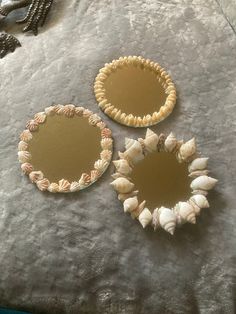 three seashell mirrors sitting on top of a bed next to a necklace and bracelet