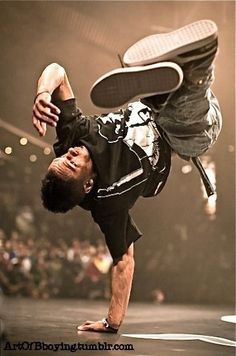 a man doing a handstand on top of a skateboard in front of an audience