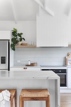 a kitchen with white cabinets and wooden stools in front of the counter top, along with a microwave oven