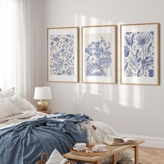 a bedroom with white walls and blue bedding, two framed pictures on the wall