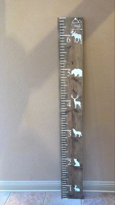 a tall wooden ruler with animals on it's side and numbers in the middle