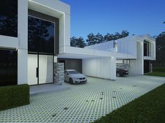 a car is parked in front of a modern house at night with its lights on