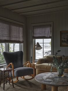 a living room filled with furniture and two windows covered in roman blind shades next to a coffee table