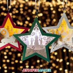 three paper stars hanging from strings with gold and silver lights in the backgroud