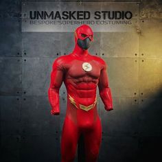 a man in a red costume standing next to a wall with the words unmasked studio on it