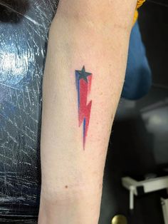 a red and blue lightning bolt tattoo on the left arm with a star in it