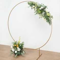 an arrangement of flowers is placed in front of a circular mirror on a wooden floor