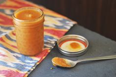 there is a spoon next to a glass jar with something in it on the table