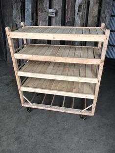 three tiered wooden shelf on wheels in front of wood planks and metal bars