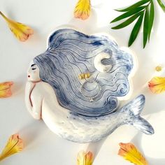 a ceramic figurine of a mermaid with rings on it's nose and tail