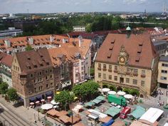 an aerial view of a city with many buildings and tables in the foreground, surrounded by trees