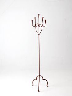 a metal coat rack with three candles on it's sides and one candle holder in the middle