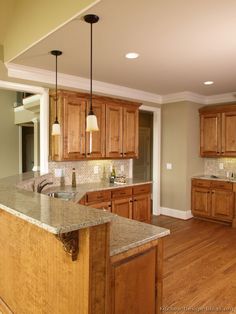 a large kitchen with wooden cabinets and granite counter tops, along with hardwood flooring