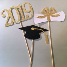 two graduation cupcake toppers with gold glitter on them