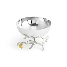 a silver bowl sitting on top of a tree branch next to a metal object with gold accents