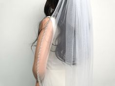 a woman wearing a wedding veil with pearls on it