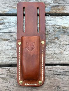 a brown leather belt case sitting on top of a wooden table