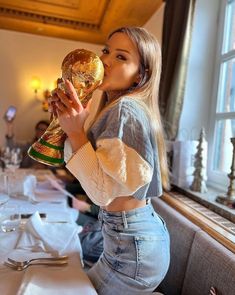 a woman sitting at a table with a trophy in her hand and looking up to the sky