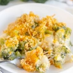 broccoli and cheese casserole on a white plate with a silver fork