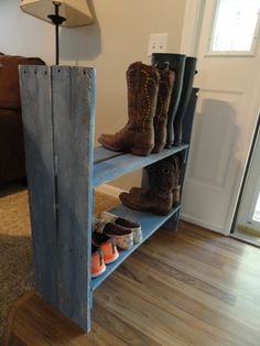 several pairs of boots sit on a shelf in the corner of a room with hardwood floors