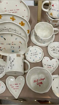 a table topped with lots of white dishes and bowls covered in handwritten words on them