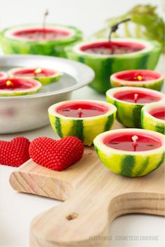 some watermelon slices are sitting on a cutting board next to bowls with candles in them