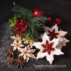 christmas cookies decorated with holly, berries and pine cones are arranged on a black surface